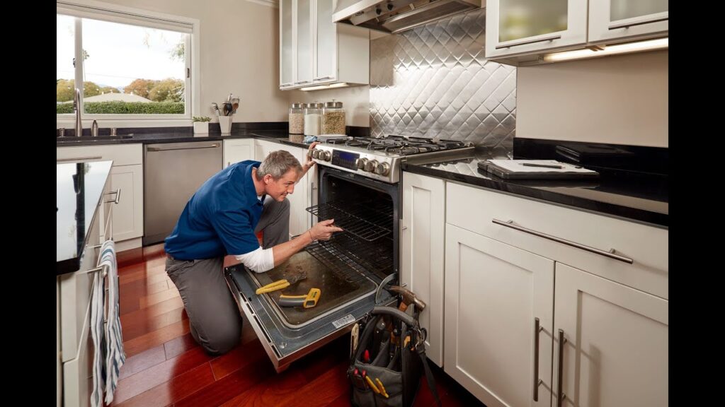 Technician inspecting an oven during appliance repair cost evaluation in a modern kitchen.