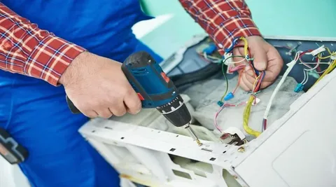 Repairman working on washing machine to determine appliance repair cost.