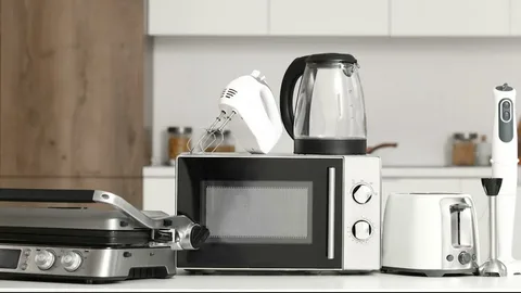 A collection of kitchen appliances, including a microwave, electric kettle, hand mixer, toaster, contact grill, and immersion blender, arranged on a countertop, highlighting the importance of regular appliance repair and maintenance for everyday household convenience.